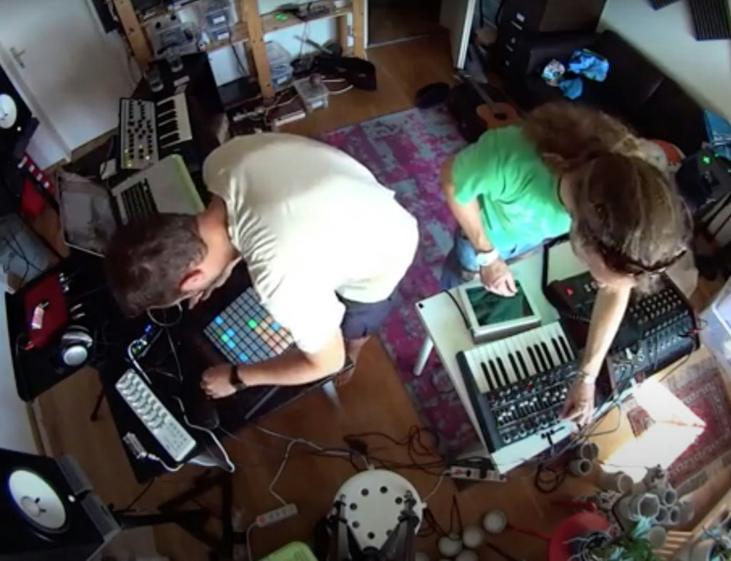 Two people making electronic music with Ableton Push and synthesizers